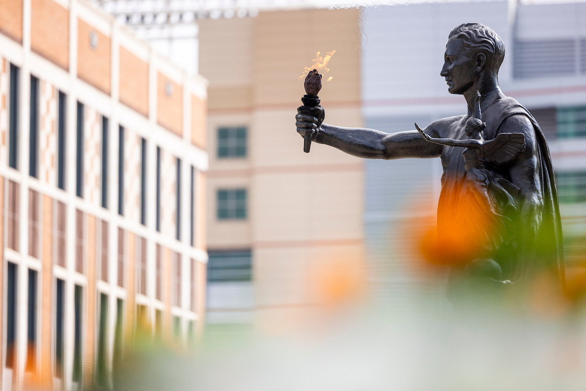 Torchbearer statue with orange marigold flowers in the foreground. Photo by Craig Bisacre/University of Tennessee.